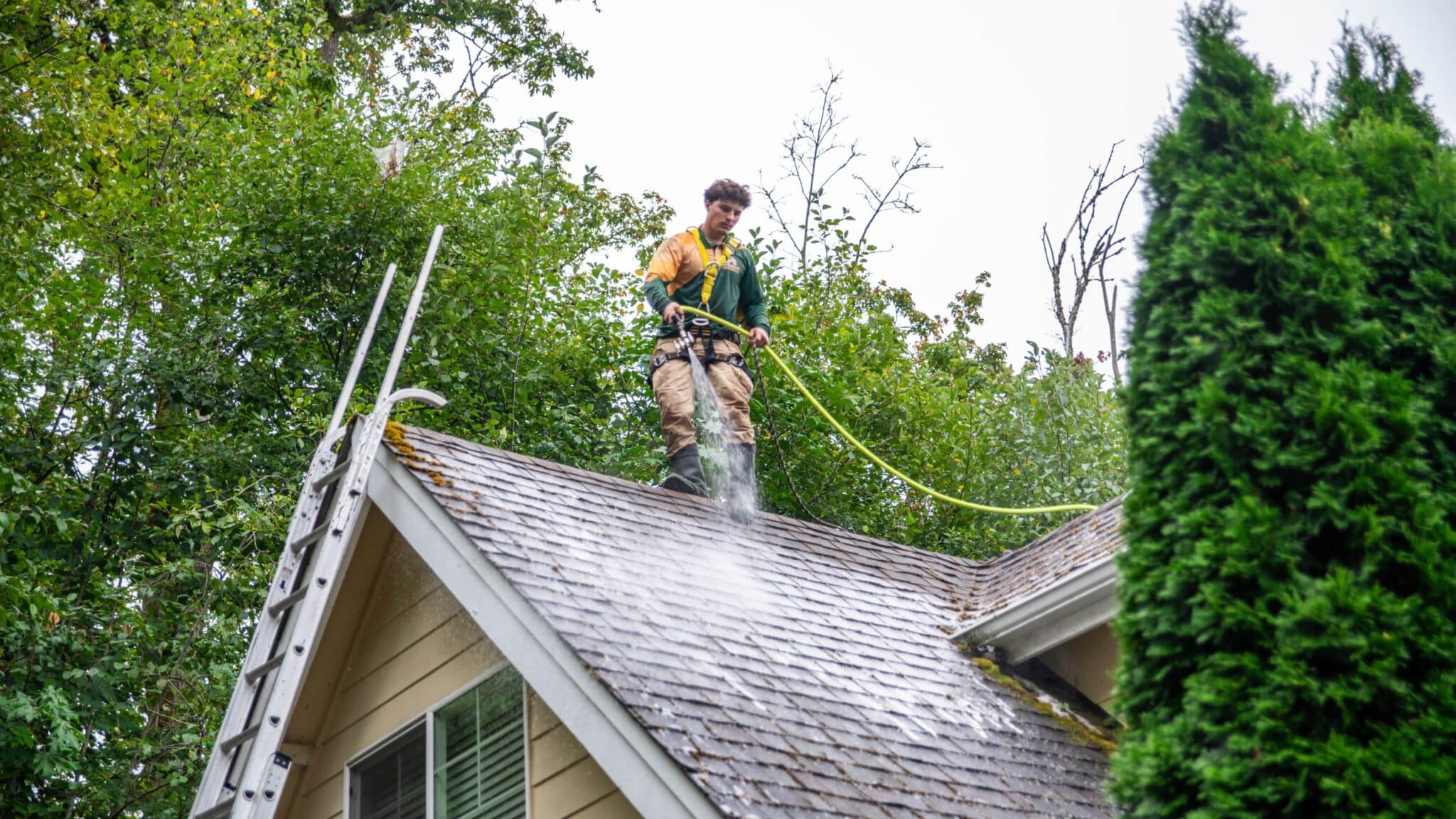Man spraying water from a hose while cleaning the rooftop.