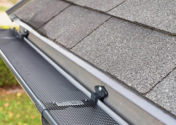 Plastic guard over new dark grey plastic rain gutter on asphalt